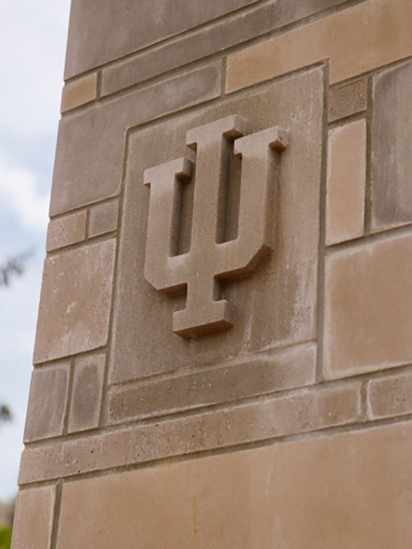 A photo of the IU trident embossed in a limestone pillar.